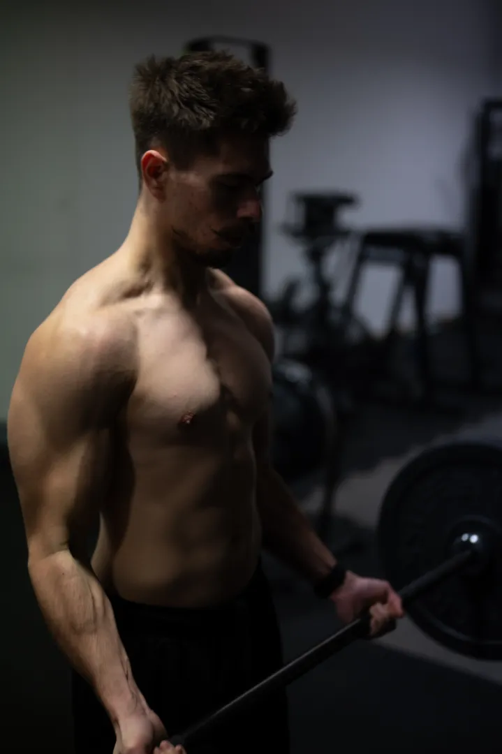 Trener personalny Patryk Michałek ćwiczy na siłowni w Bydgoszczy ze sztangą.